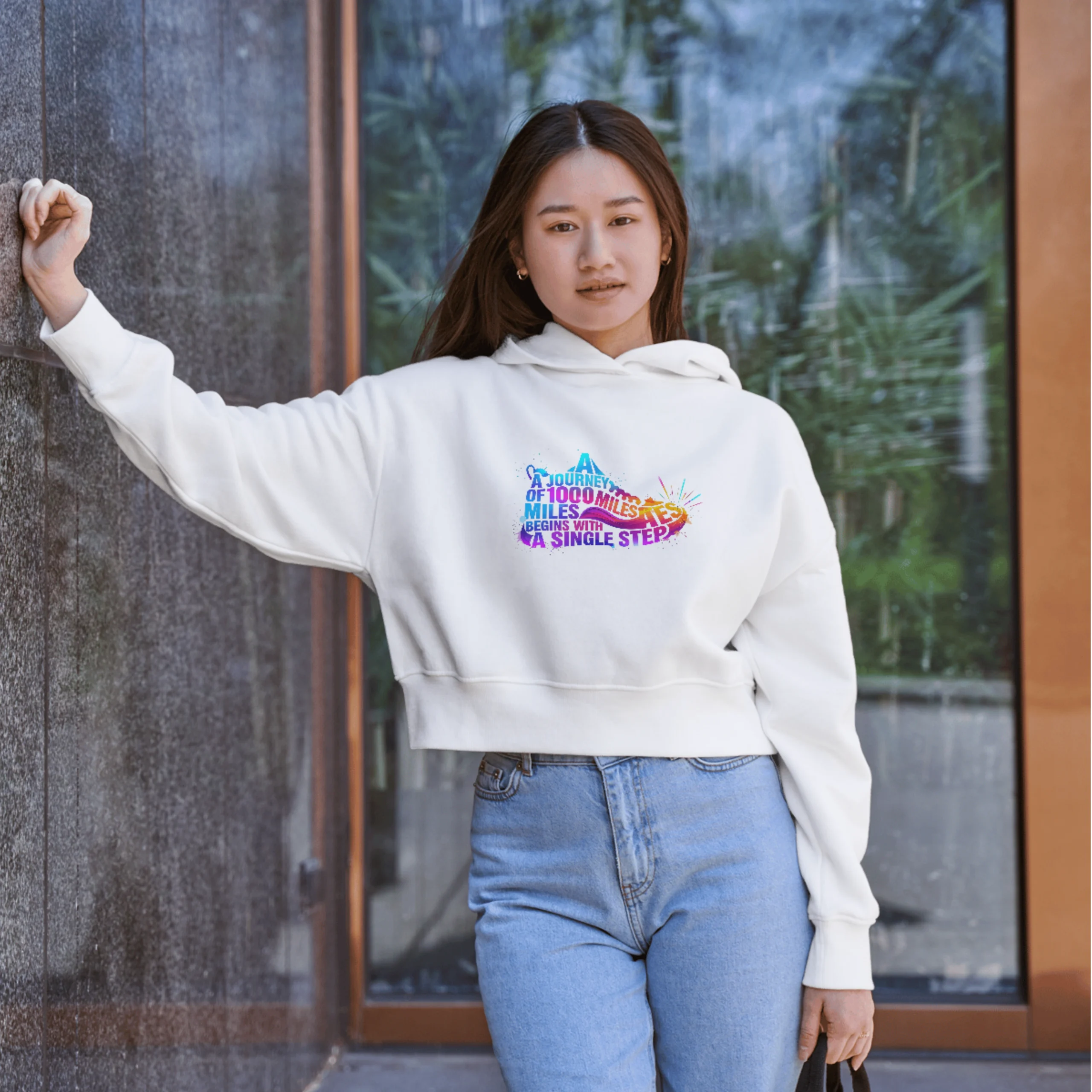 Man and woman modeling the matching QGM 'Journey of 1000 Miles' white unisex graphic tee with a vibrant, colorful running shoe design.